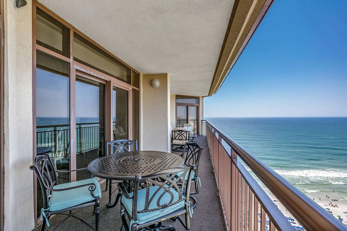 This image features a serene balcony with a dining table and railing overlooking a stunning ocean view. The scene captures the tranquil ambiance of enjoying outdoor dining, sunbathing, or simply relaxing while taking in the sunrise and the calming sea breeze.