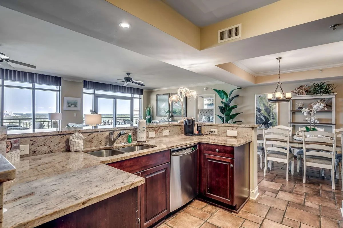 A bright, elegant dining area adjacent to a modern kitchen with granite countertops and stainless steel appliances. Large windows allow sunlight to flood the space, and the dining table is set for gatherings with loved ones. The seamless connection to the living area supports easy entertaining.